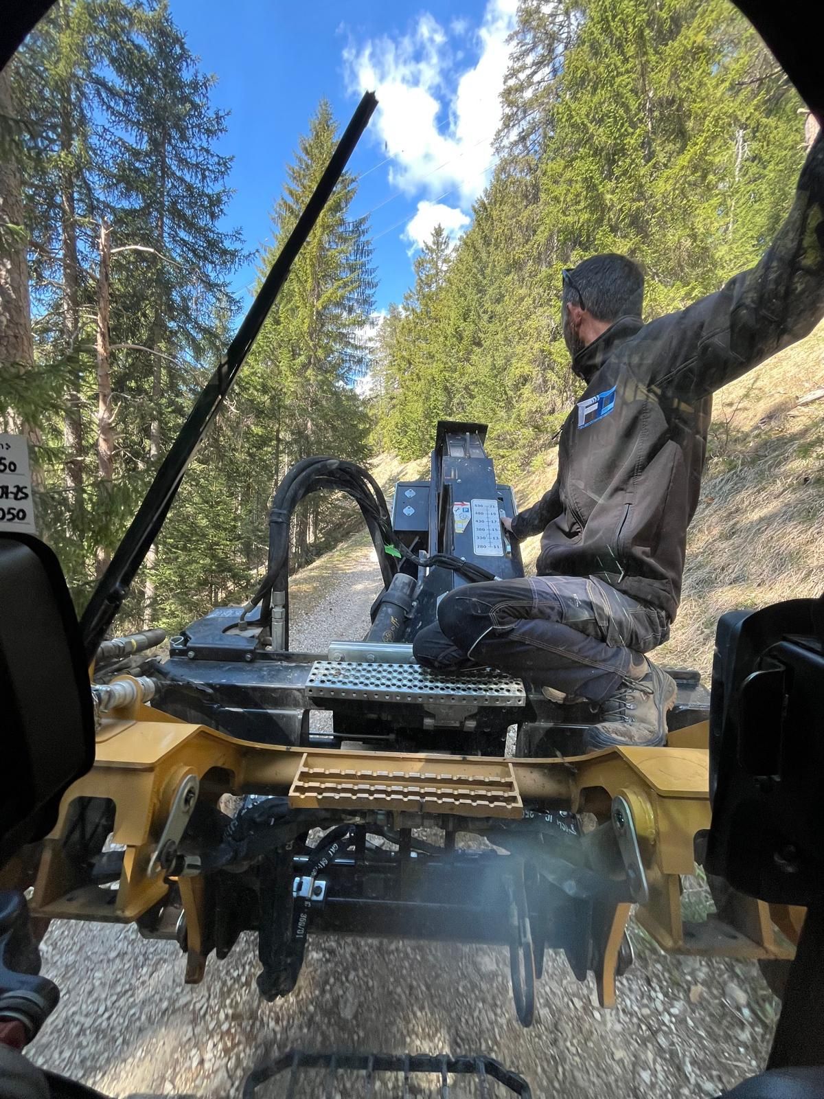 Operatore accanto alla macchina su una pista forestale sterrata tra i boschi